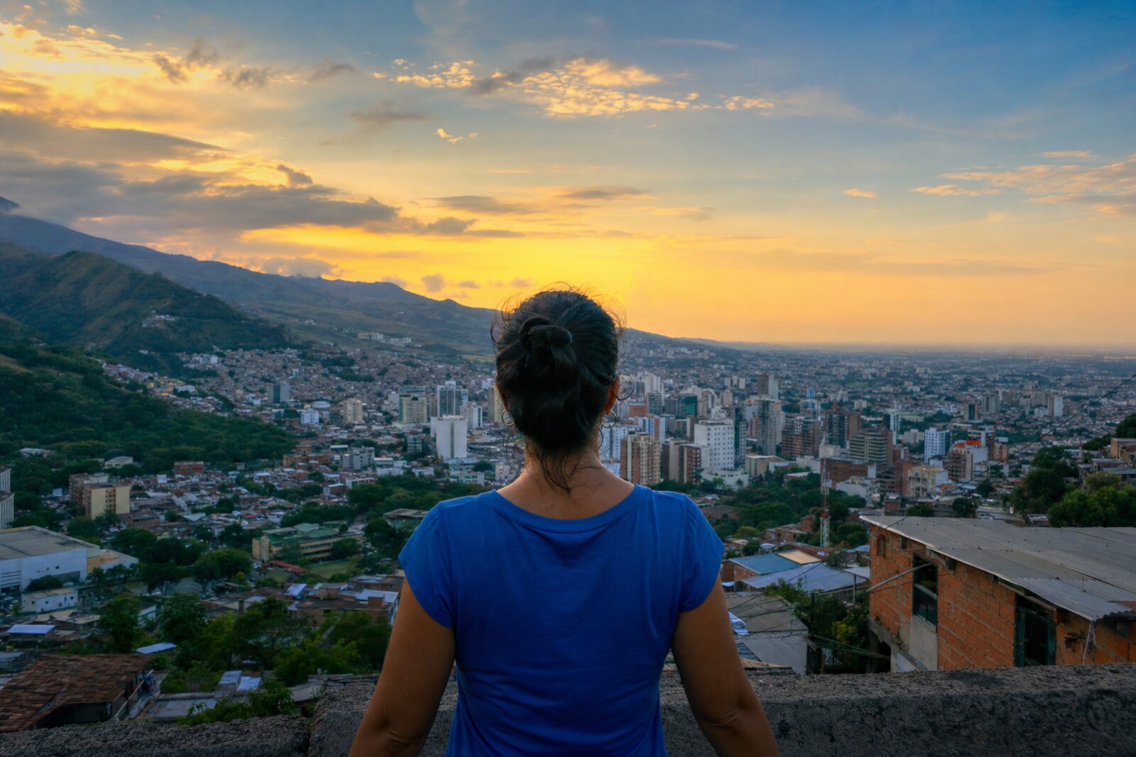 Mujer contemplando la ciudad de Cali al atardecer